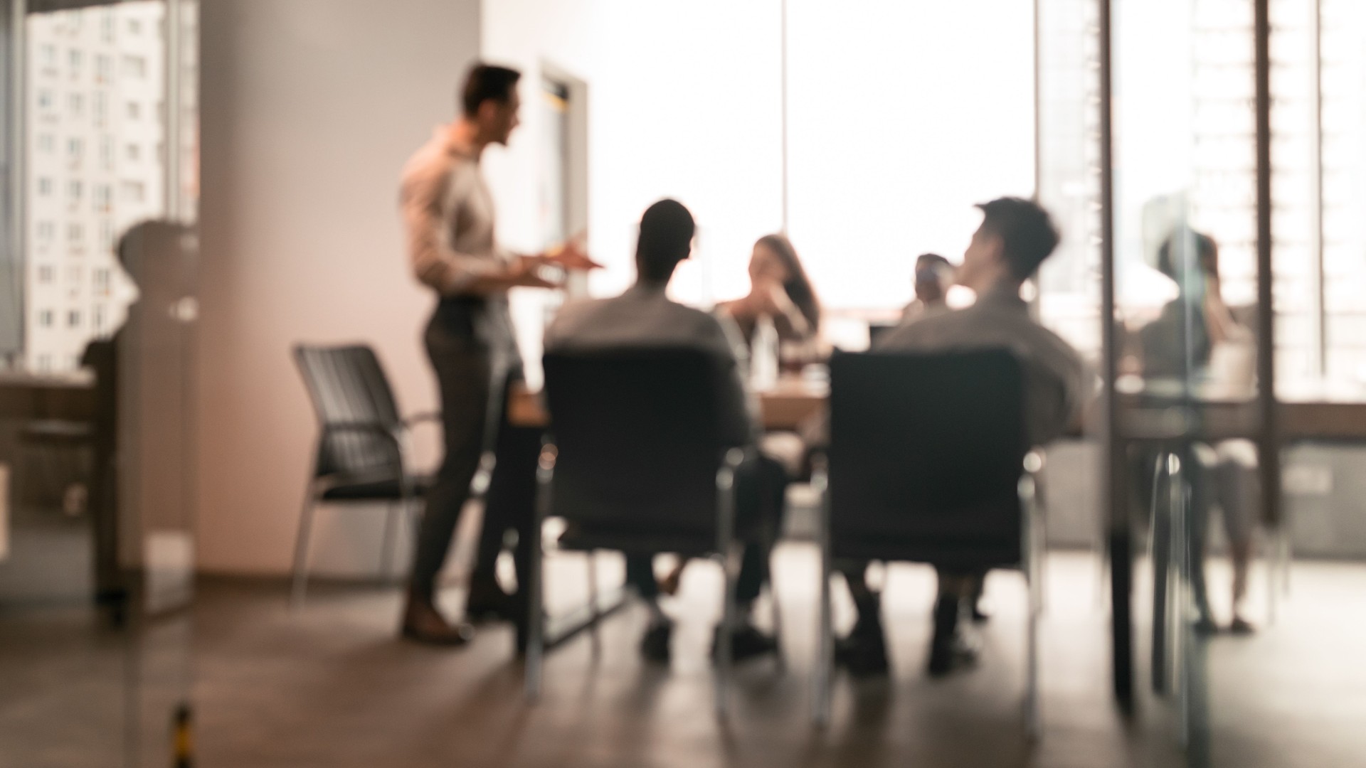 Colleagues having meeting in boardroom, businessman giving speech, blurred photo